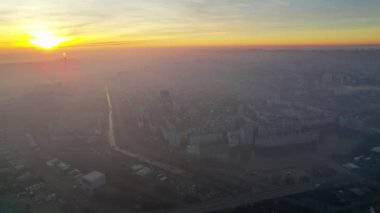 Aerial drone view of Chisinau at sunrise, Moldova. View of the city with fog in the air, multiple buildings, roads, lake, bare trees