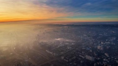 Aerial drone timelapse view of Chisinau at sunrise, Moldova. View of the city with fog in the air, multiple buildings, roads, bare trees