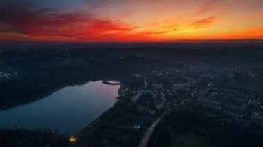 Aerial drone timelapse view of Chisinau at sunset, Moldova. View of city centre with lake, buildings, roads, illumination