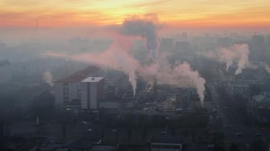 Aerial drone view of an production facility in Chisinau at sunrise, Moldova. Cityscape with multiple buildings, pipes with felling steam