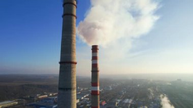 Aerial drone view of thermal power plant in Chisinau, Moldova. View of pipes with felling steam, cityscape, forest on the background