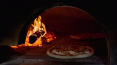 Pizza cooking on a brick oven with wood fire at an italian restaurant in Napoli