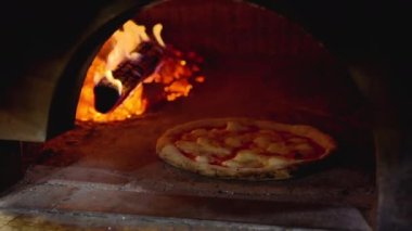 Pizza cooking on a brick oven with wood fire at an italian restaurant in Napoli