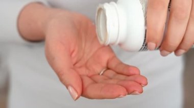 Evde vitamin hapı alan bir kadın var.