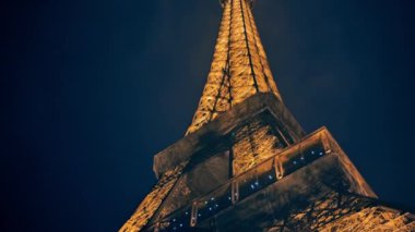 Close view of the illuminated Eiffel Tower in Paris at night, France. Multiple nightlights, bottom view, rising elevator