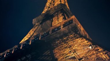 Close view of the illuminated Eiffel Tower in Paris at night, France. Multiple nightlights, bottom view, rising elevator
