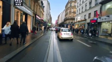 PARIS, FRANCE - JANUARY, 2022: Street view of the city. Street with classic buildings, walking people and moving cars, cloudy weather