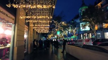 PARIS, FRANCE - DECEMBER, 2022: Street view of city downtown at night. A lot of illumination, walking people, classic buildings