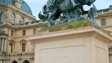 View of the Louis XIV Statue on the Napoleon Courtyard in Paris, France. Louvre Palace on the background, cloudy weather