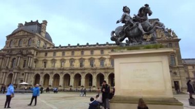PARIS, FRANCE - DECEMBER, 2022: View of the Louis XIV Statue on the Napoleon Courtyard. Louvre Palace, tourists, cloudy weather