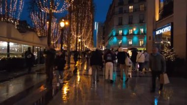 PARIS, FRANCE - DECEMBER, 2022: Street view of city downtown at night. A lot of illumination, walking people, classic buildings