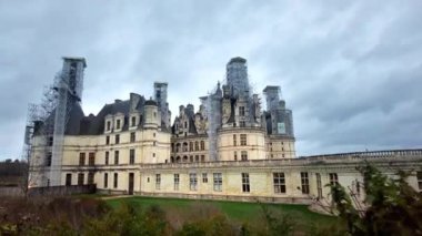 Ön planda çıplak ağaçlar ve bulutlu hava Fransa 'da Chambord Şatosu manzarası