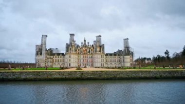 View of the Chateau de Chambord with gardens and fortress moat around it, cloudy weather, France