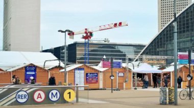 PARIS, FRANCE - DECEMBER, 2022: Slow motion view of the Christmas fair in business centre, modern buildings, walking people