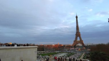 PARIS, FRANCE - DECEMBER, 2022: View of the Eiffel Tower from the Trocadero Square with multiple people at sunset. Gardens of the Trocadero with people, cityscape