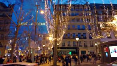 PARIS, FRANCE - 2022 ARALIK: Bir sürü aydınlanma, yürüyen insanlar, klasik binalar, dükkanlar.