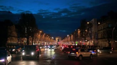 PARIS, FRANCE - DECEMBER, 2022: Street view of the city downtown at night. Street with traffic and illumination, The Triumphal Arch in the distance