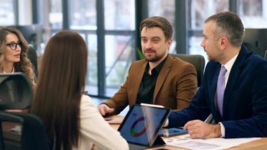 Business meeting in an office, workers discussing business affairs. Gadgets and papers with charts on the table