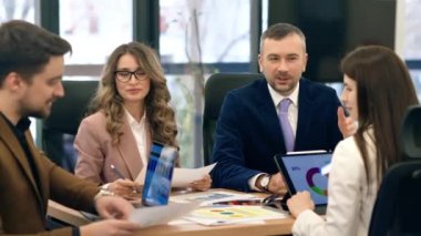 Business meeting in an office, workers discussing business affairs. Gadgets and papers with charts on the table