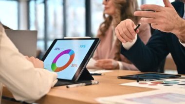 Business meeting in an office, workers discussing business affairs. Tablet with charts and papers on the table. Slow motion