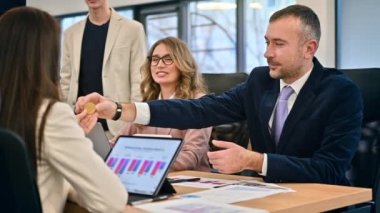 Business meeting in an office, workers discussing the topic of cryptocurrencies using a physical coin. Gadgets and papers on the table. Slow motion