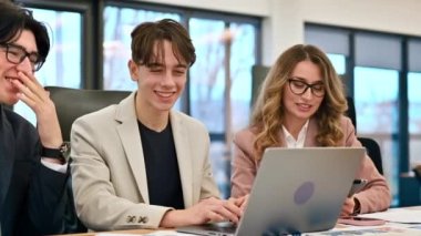 Business meeting in an office, female team leader and two young workers discussing business affairs using gadgets and papers. Slow motion