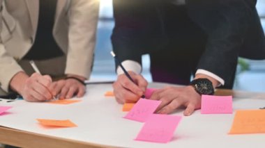 Business meeting in an office, close view of workers taking notes on sticky papers. Slow motion