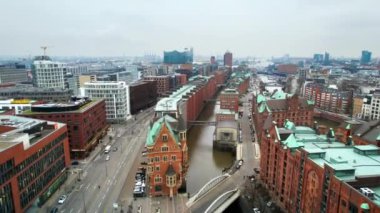 Aerial drone view of Speicherstadt in Hamburg, Germany. Classic buildings, water channels, sea port and roads with cars. Cloudy weather