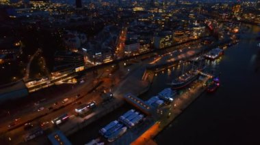 Aerial drone view of Hamburg at evening, Germany. Elbe coastline, moored boats, sea port, classic and modern buildings, roads with cars and nightlights