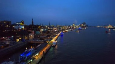 Aerial drone view of Hamburg at evening, Germany. Elbe coastline, moored boats, sea port, classic and modern buildings, roads with cars and nightlights