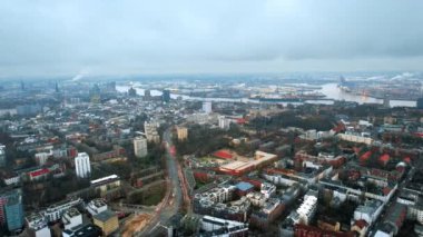 Hamburg, Almanya 'nın hava aracı görüntüsü. Klasik ve modern binalar, arabalı yollar ve çıplak ağaçlar, uzaktaki deniz limanı. Bulutlu hava