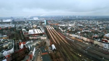 Aerial drone view of Hamburg, Germany. Classic and modern buildings, railway station, roads with cars and bare trees, sea port in the distance. Cloudy weather