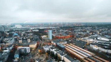 Aerial drone view of Hamburg, Germany. Classic and modern buildings, railway station, roads with cars and bare trees, sea port in the distance. Cloudy weather