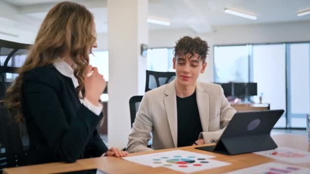 办公室里的商务会议 一个女人和一个年轻人在谈生意 带有图表和注释的小工具 慢动作 — 图库视频影像