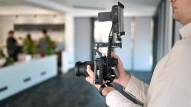 Dış görünüşü olan bir kamera tutan profesyonel bir fotoğrafçı. Ofiste çekim yapmak. Yavaş çekim