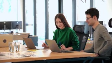 Team leader discussing business affairs with a female worker using charts. Business meeting at the office. Papers and tablet on the table