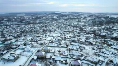 Aerial drone view of a village in Moldova in winter. Residential buildings, roads and fields covered with snow, bare trees