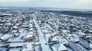 Moldova 'daki bir köyün kışın hava aracı görüntüsü. Yerleşim yerleri, yollar ve tarlalar karla kaplı, çıplak ağaçlar