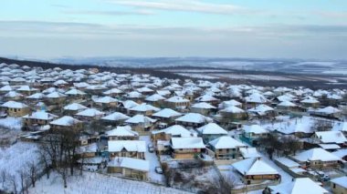 Moldova 'daki bir köyün kışın hava aracı görüntüsü. Yerleşim yerleri, yollar ve tarlalar karla kaplı, çıplak ağaçlar