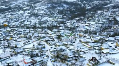Aerial drone view of a village in Moldova in winter. Residential buildings, church and roads covered with snow, bare trees