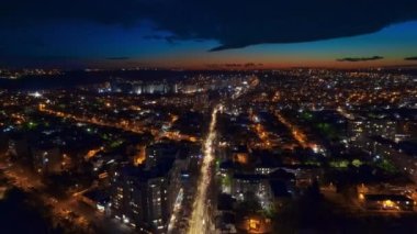 Aerial drone timelapse view of Chisinau at evening, Moldova. View of the city with multiple buildings, roads with moving cars, illumination