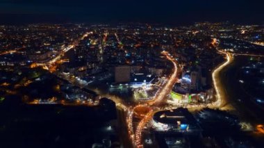Aerial drone timelapse view of Chisinau at night, Moldova. View of the city with multiple buildings, roundabout with moving cars, illumination
