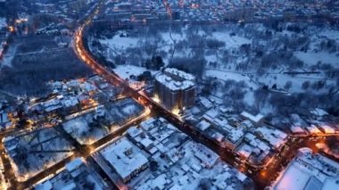Kışın gün batımında Chisinau 'nun hava aracı görüntüsü Moldova' da. Karla kaplı binalar, yollar ve parklar, hareket eden arabalar, aydınlatma