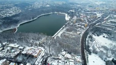 Aerial drone view of Chisinau in winter, Moldova. View of the Valea Morilor park with lake and bare trees, buildings around it