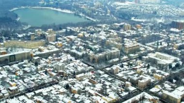 Aerial drone view of Chisinau in winter, Moldova. View of the city with multiple buildings and roads covered with snow, Valea Morilor park with lake and bare trees