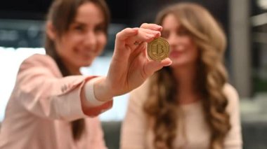 Happy woman showing golden bitcoin at the office