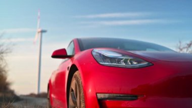 Red car close up near wind turbine generator