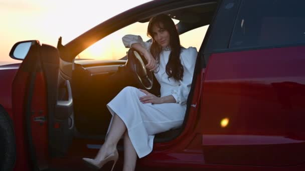 Gün Batımında Kırmızı Bir Arabada Beyaz Elbiseli Mutlu Bir Kadın — Stok video