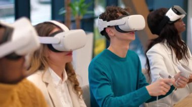 VR 'da bir ofiste iş konferansı. Çok ırklı bir grup insan. Genç bir adam masadaki VR gözlüklerini, kumandayı, kağıtları ve aletleri kullanmayı öğretiyor.