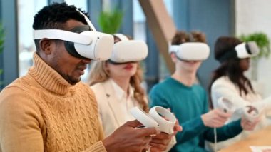 VR 'da bir ofiste iş konferansı. VR gözlük ve kumanda kullanan çok ırklı bir grup insan. Yavaş çekim